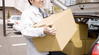 車からダンボールを運ぶ人の画像